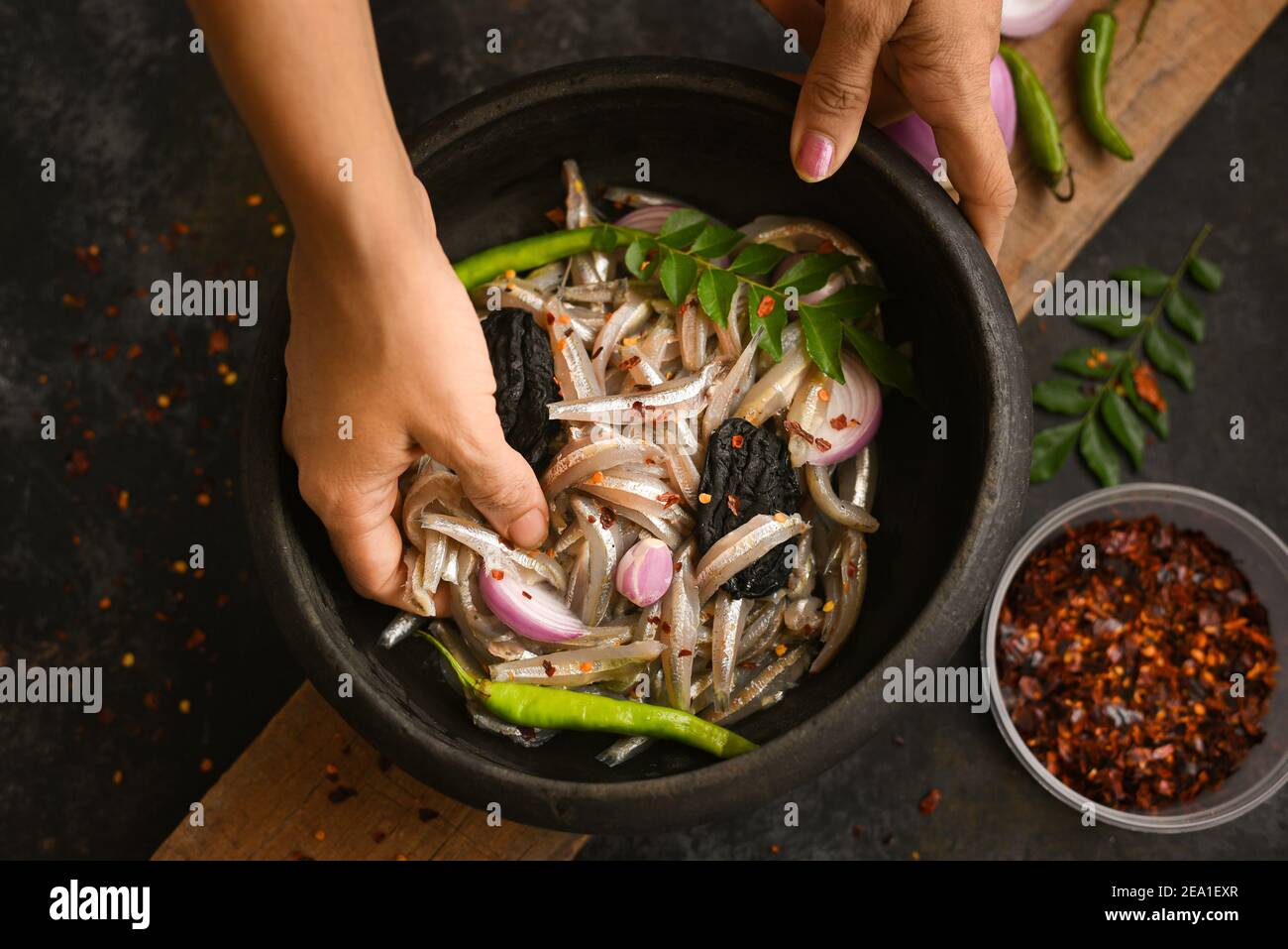 Top view spicy hot anchovy Kerala fish curry. Indian food. Woman hand