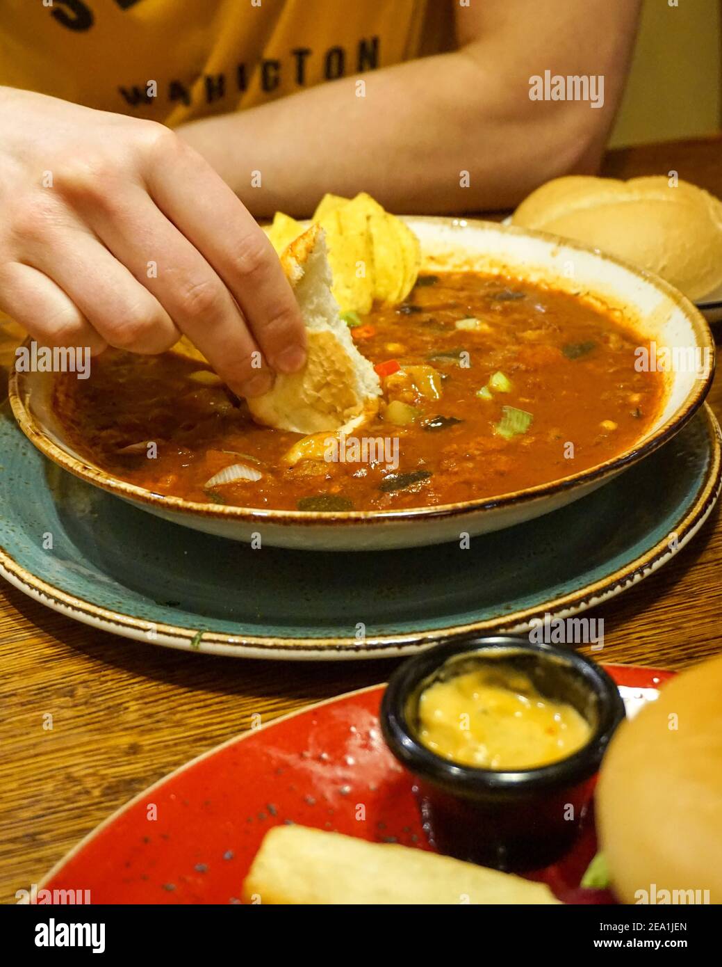 Dipping bread into Spicy bean soup, dip nachos, Chiquito Mexican Chain Restaurant - Casual dining, vegan plant based food menu Stock Photo