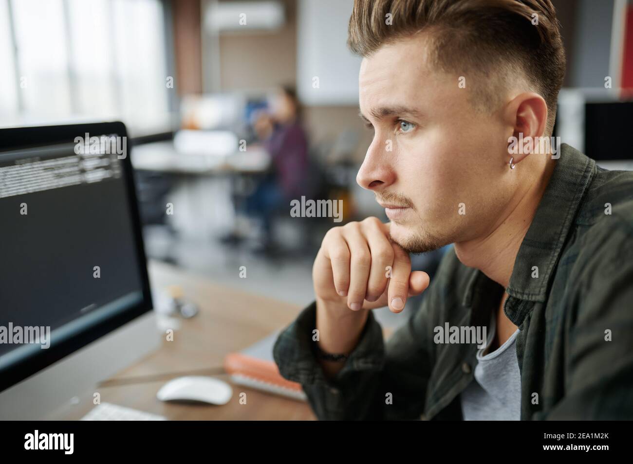 Thoughtful male IT specialist sits at the table Stock Photo