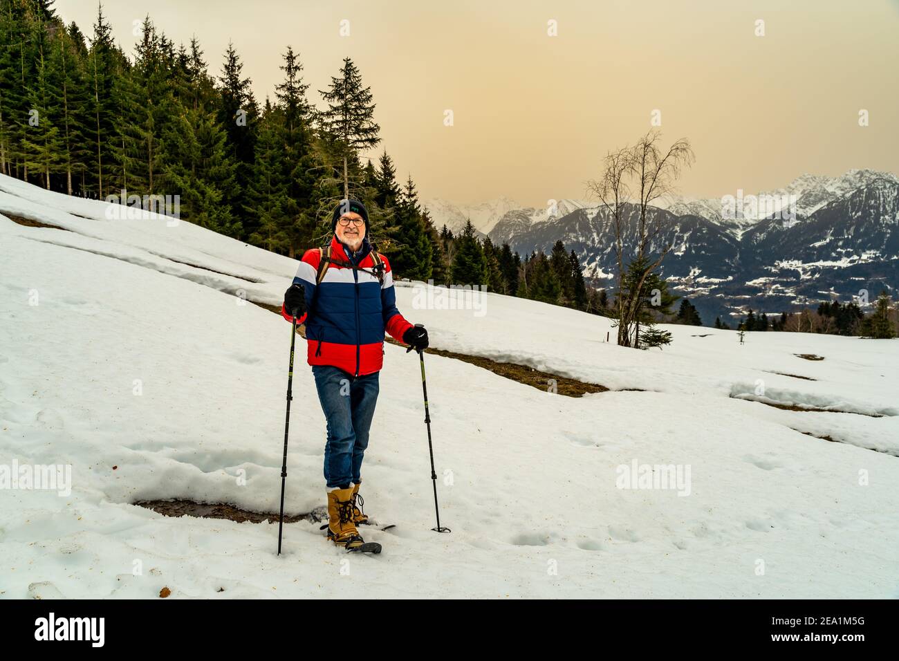 Dieter hike with snowshoes over the Walgau in the snowy Vorarlberg. Schneeschuhwanderung im Hochmoor über Sateins mit Saharasand am Himmel. Stadel Stock Photo