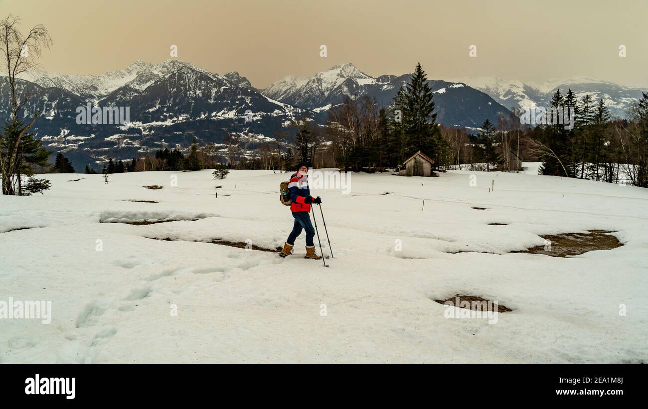 Dieter hike with snowshoes over the Walgau in the snowy Vorarlberg. Schneeschuhwanderung im Hochmoor über Sateins mit Saharasand am Himmel. Stadel Stock Photo