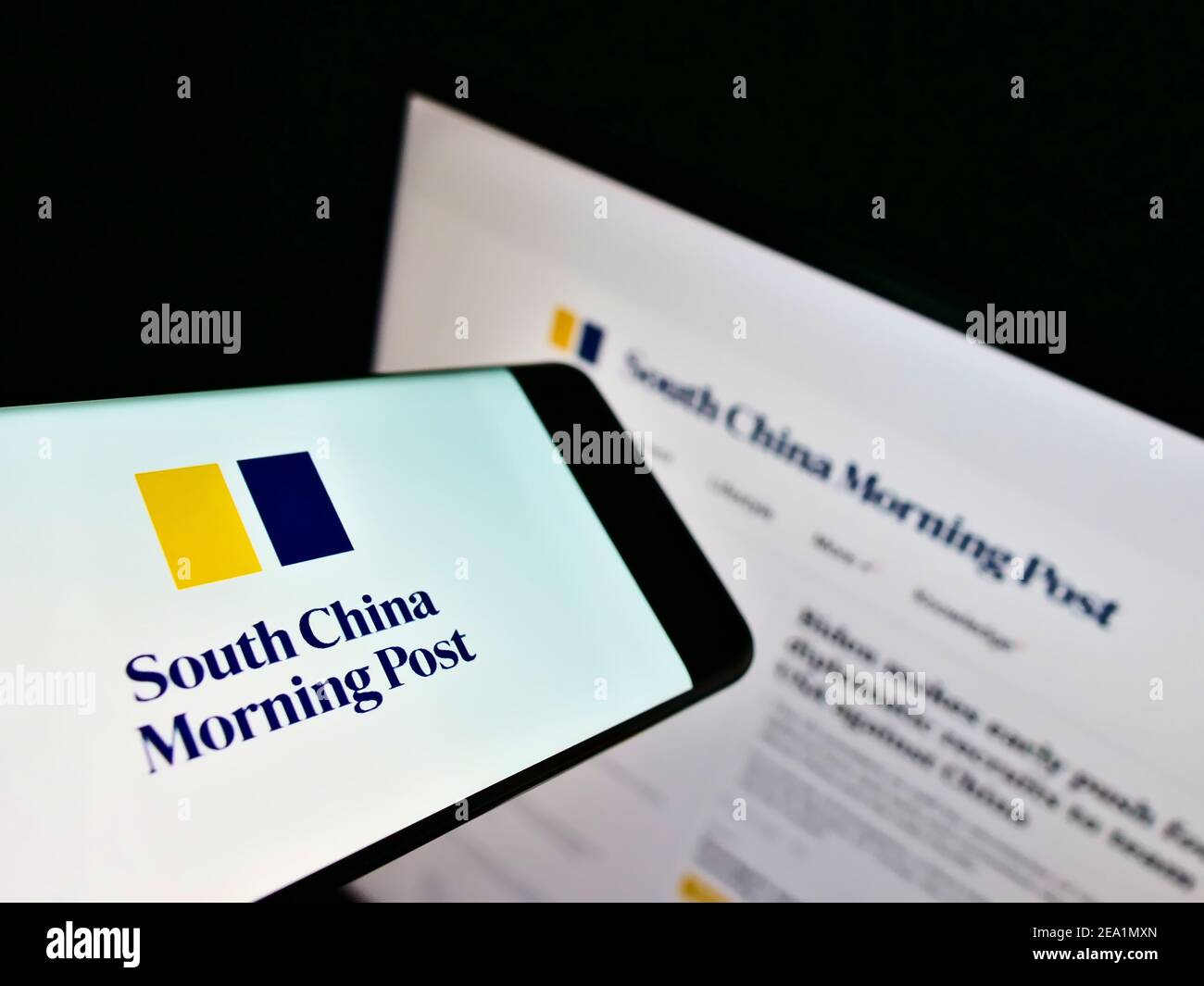 Mobile phone with logo of newspaper South China Morning Post (Hongkong) on screen in front of company website. Focus on center-right of phone display. Stock Photo