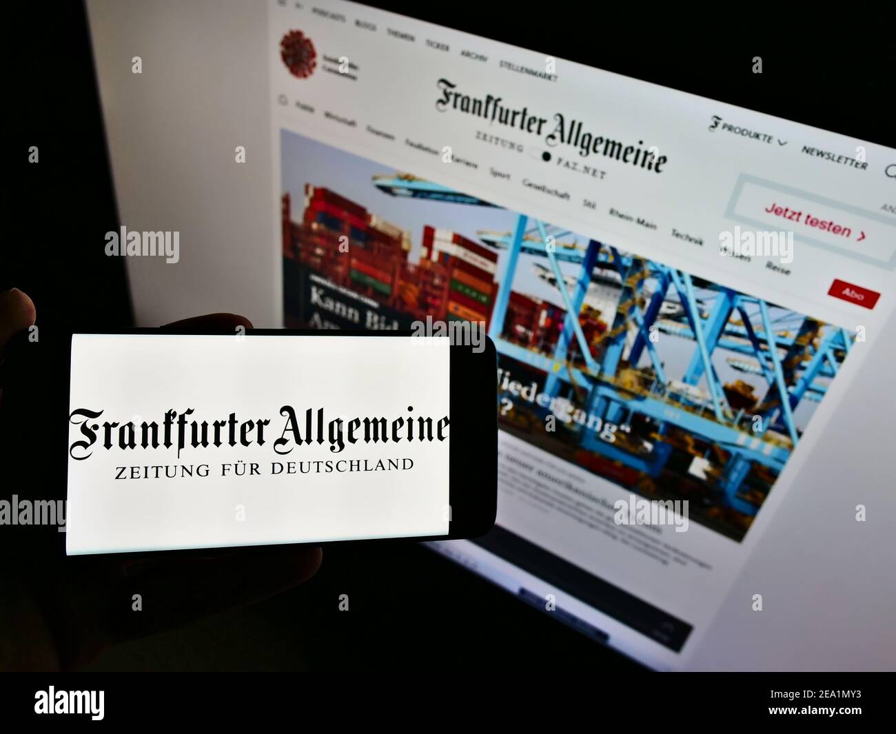 Person holding smartphone with logo of German newspaper Frankfurter Allgemeine Zeitung (FAZ) on screen in front of website. Focus on phone display. Stock Photo