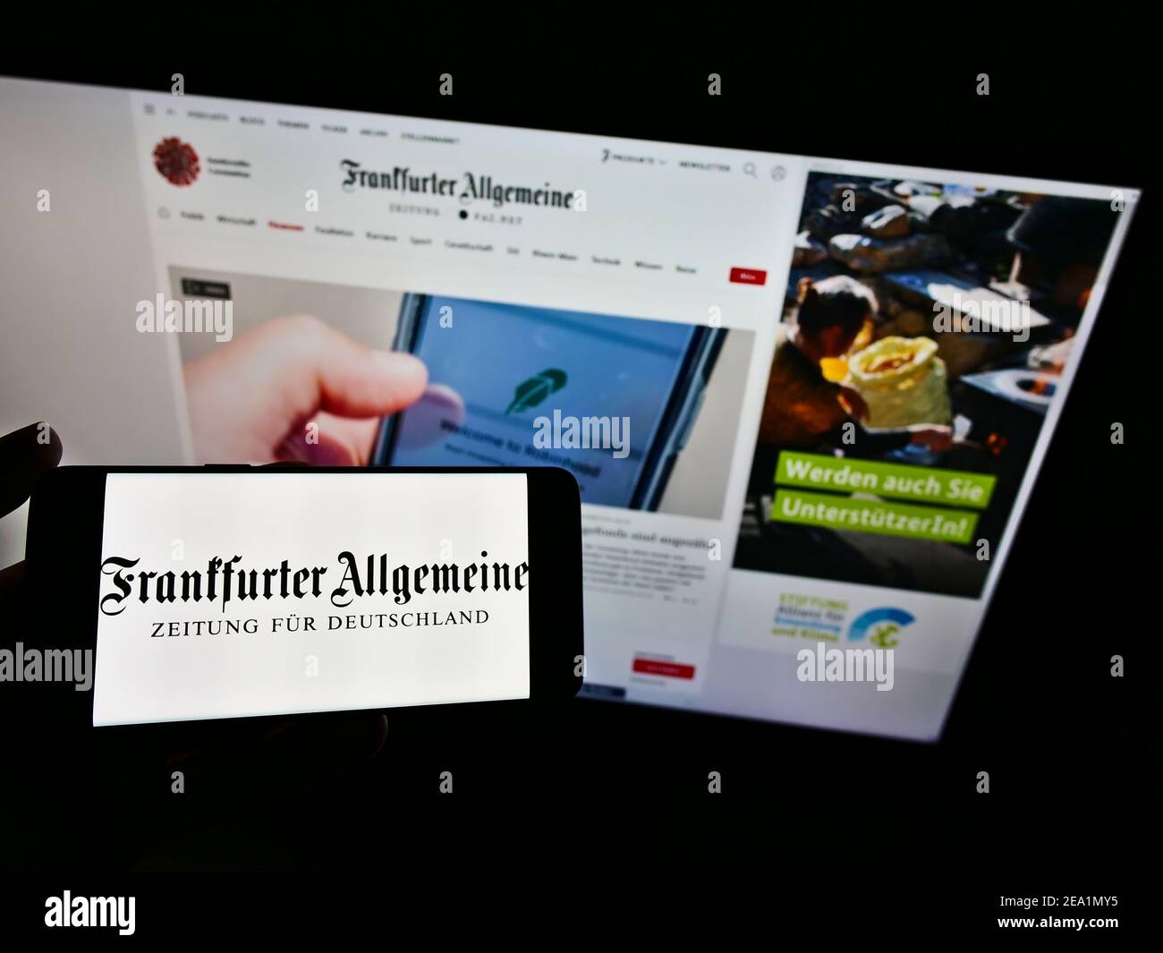 Person holding mobile phone with logo of German newspaper Frankfurter Allgemeine Zeitung (FAZ) on screen in front of website. Focus on phone display. Stock Photo