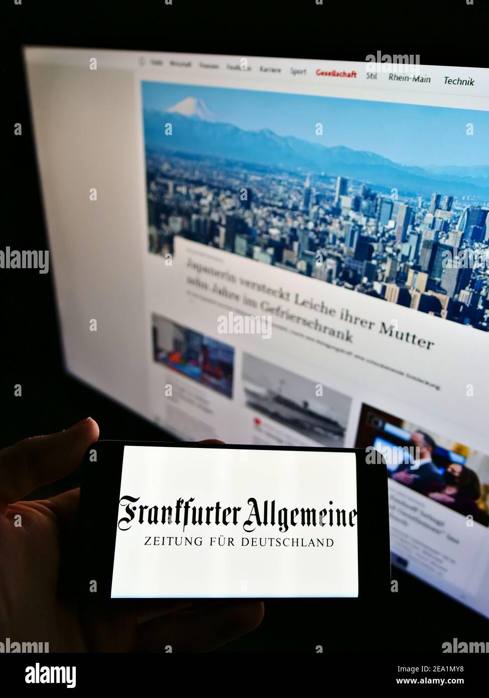 Person holding mobile phone with logo of German newspaper Frankfurter Allgemeine Zeitung (FAZ) on screen with website. Focus on cellphone display. Stock Photo