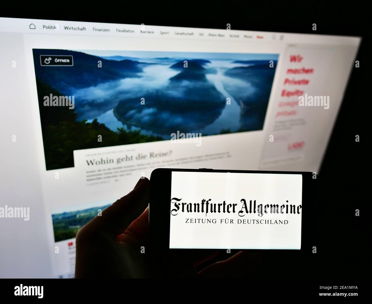 Person holding smartphone with logo of German newspaper Frankfurter Allgemeine Zeitung (FAZ) on screen in front of web page. Focus on phone display. Stock Photo