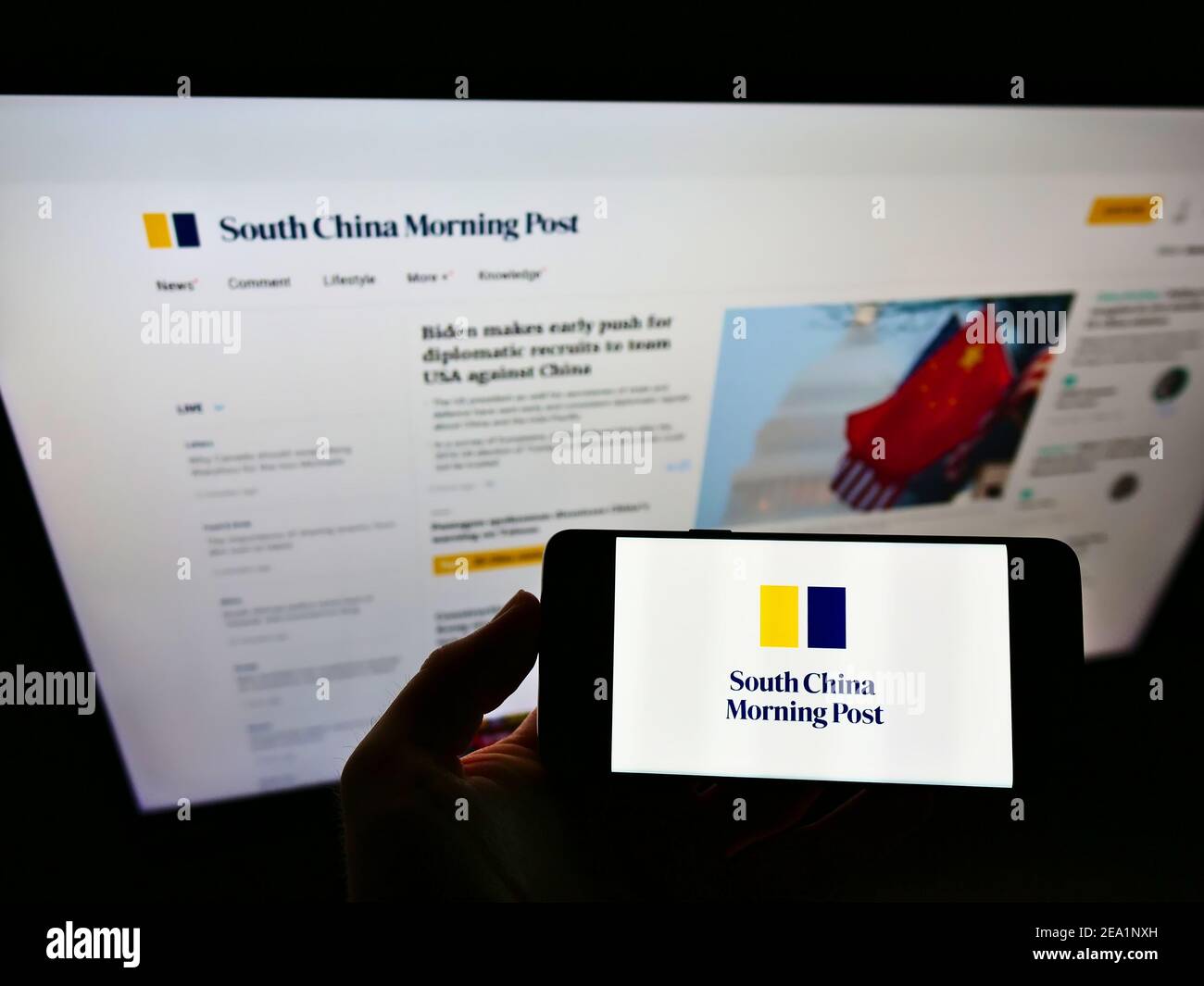 Person holding smartphone with logo of newspaper South China Morning Post (Hongkong) on screen in front of company website. Focus on phone display. Stock Photo