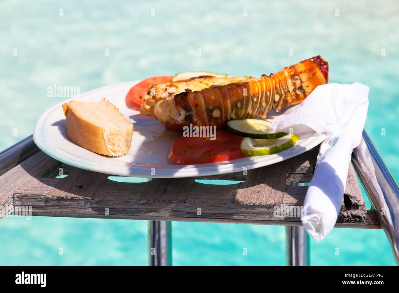 plate with lobster langouste on a yacht against the backdrop of the azure waters of the Caribbean Sea. Cuba Stock Photo
