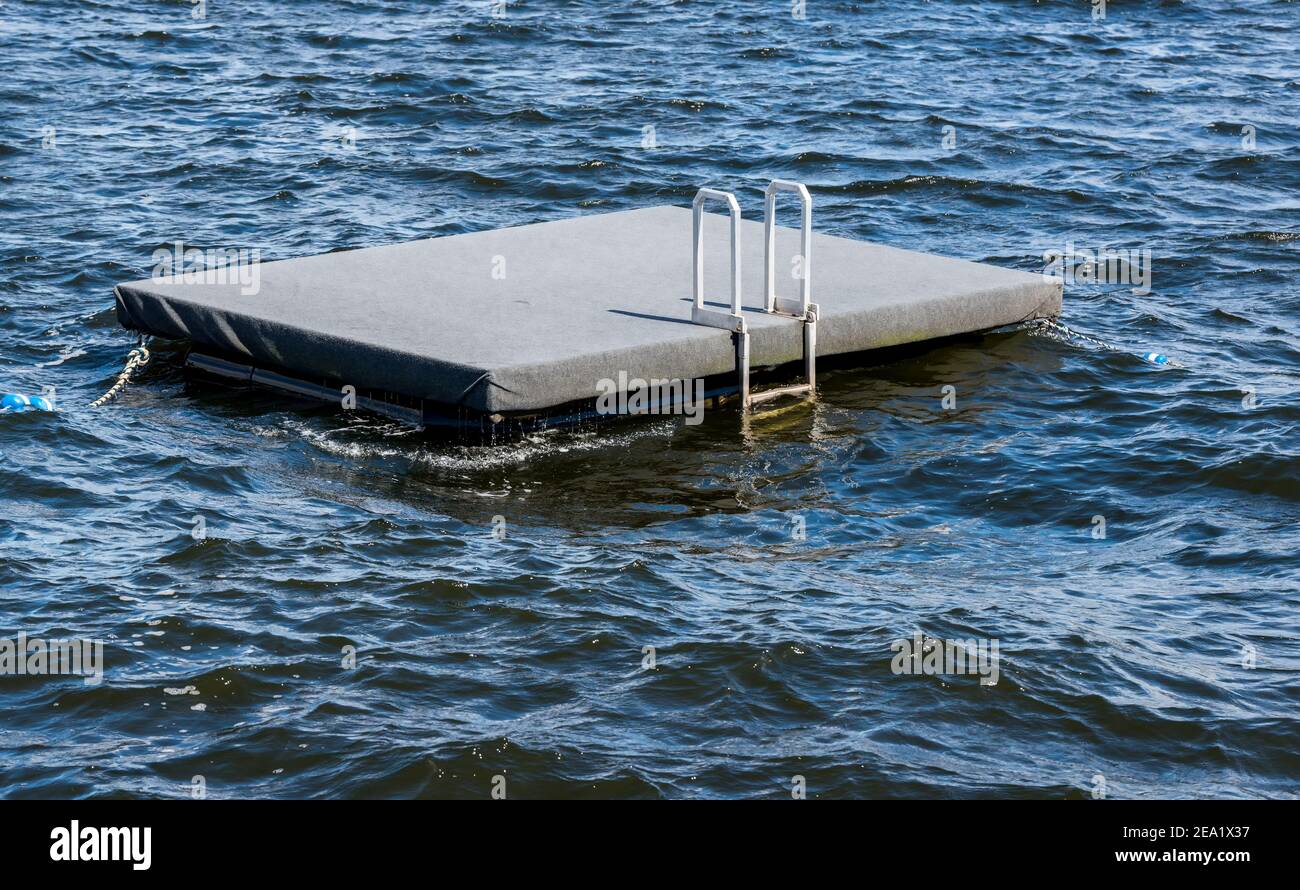 Small diving platform in choppy water. This is the type of platform used in lakes and rivers. Focus on closest corner.  Room for text. Stock Photo