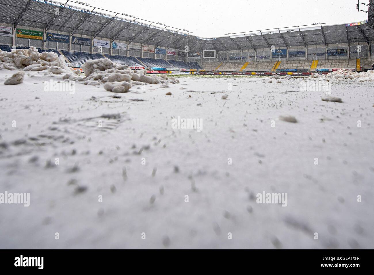 07 February 2021, North Rhine-Westphalia, Paderborn: Football: 2. Bundesliga, SC Paderborn 07 - 1. FC Heidenheim, Matchday 20, at Benteler-Arena. View into the empty stadium with snow-covered turf. Helpers had been clearing the pitch of snow since early morning. Due to the heavy snowfall, the match was nevertheless cancelled shortly before kick-off. Photo: David Inderlied/dpa - IMPORTANT NOTE: In accordance with the regulations of the DFL Deutsche Fußball Liga and/or the DFB Deutscher Fußball-Bund, it is prohibited to use or have used photographs taken in the stadium and/or of the match in the Stock Photo