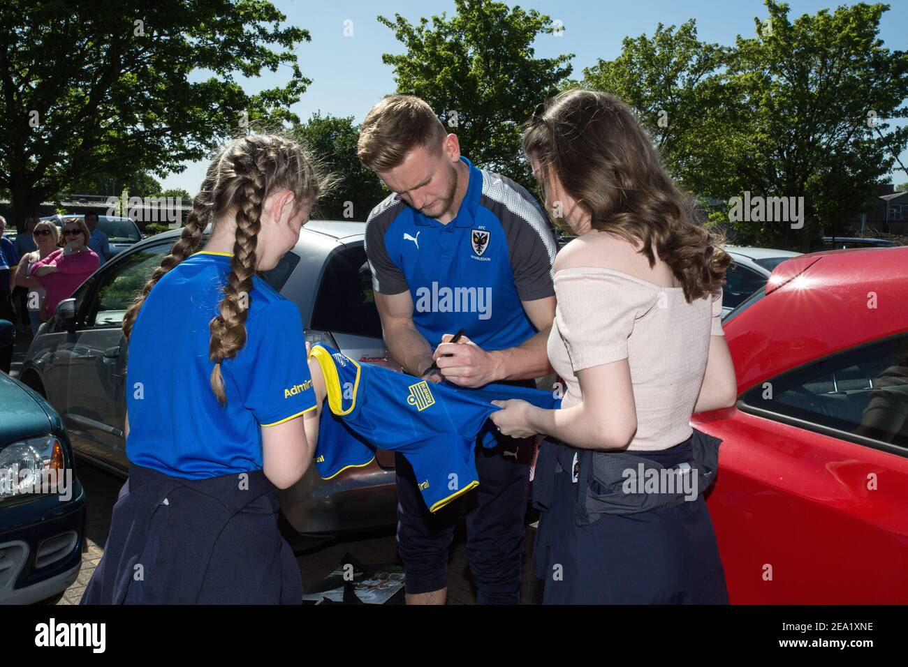 AFC Wimbledon football player signing football shirts for two female fans England Stock Photo