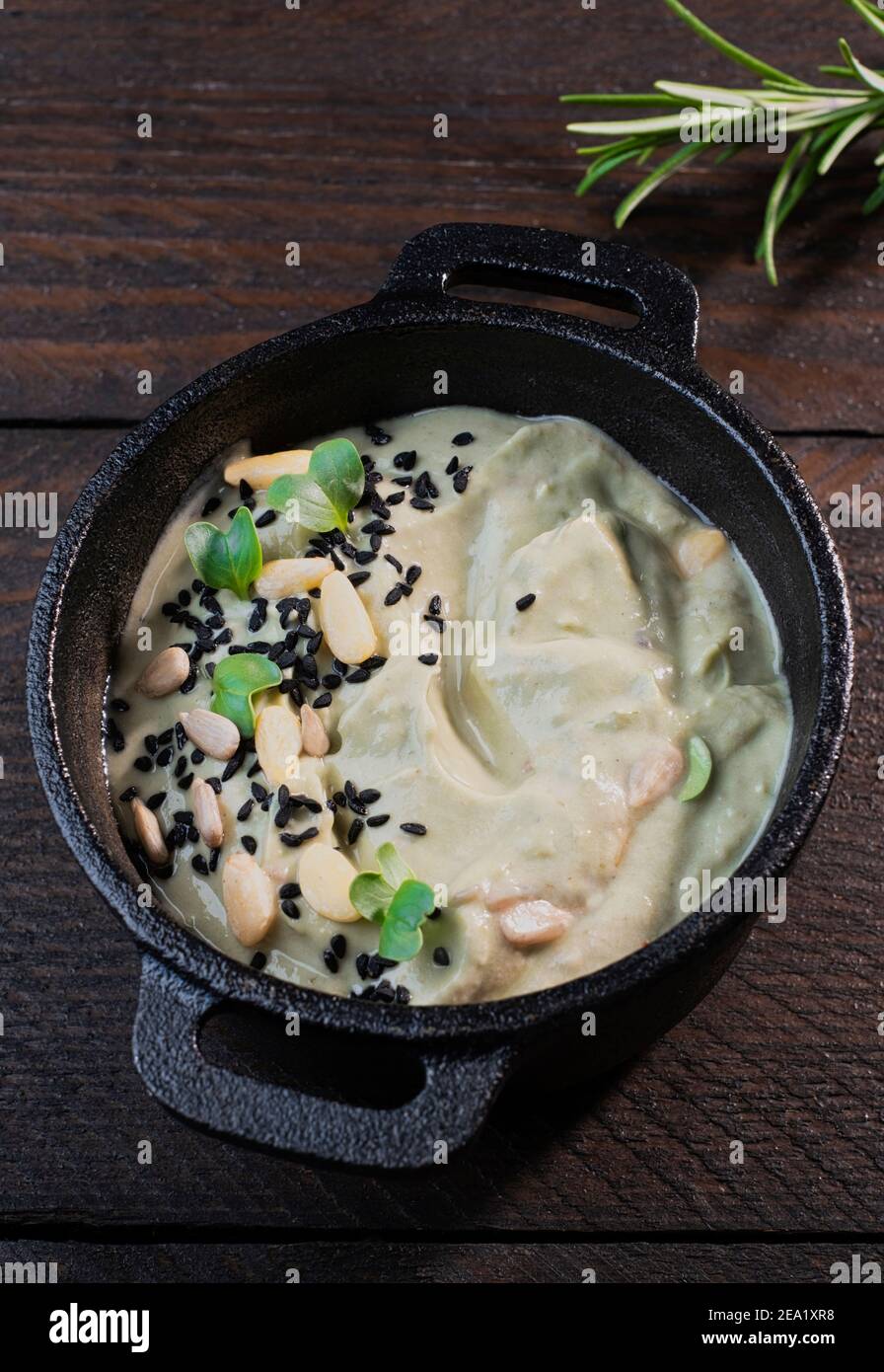 Avocado dip arranged in a black cast iron top, decorated with rosemary Stock Photo