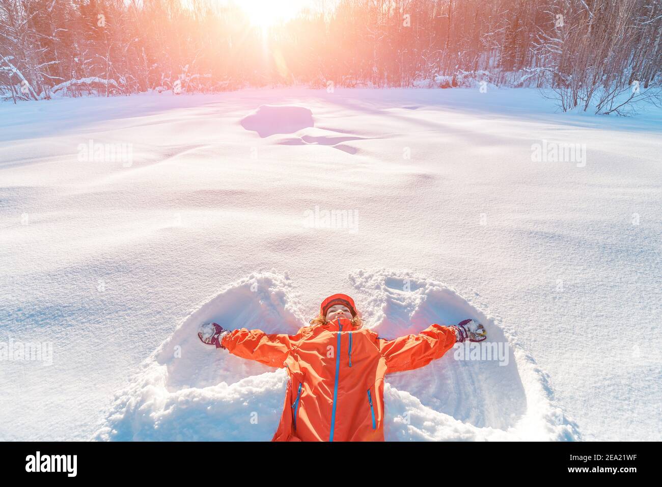 A young woman makes a snow angel lying in the snow with her arms and legs  spread to the sides Stock Photo - Alamy