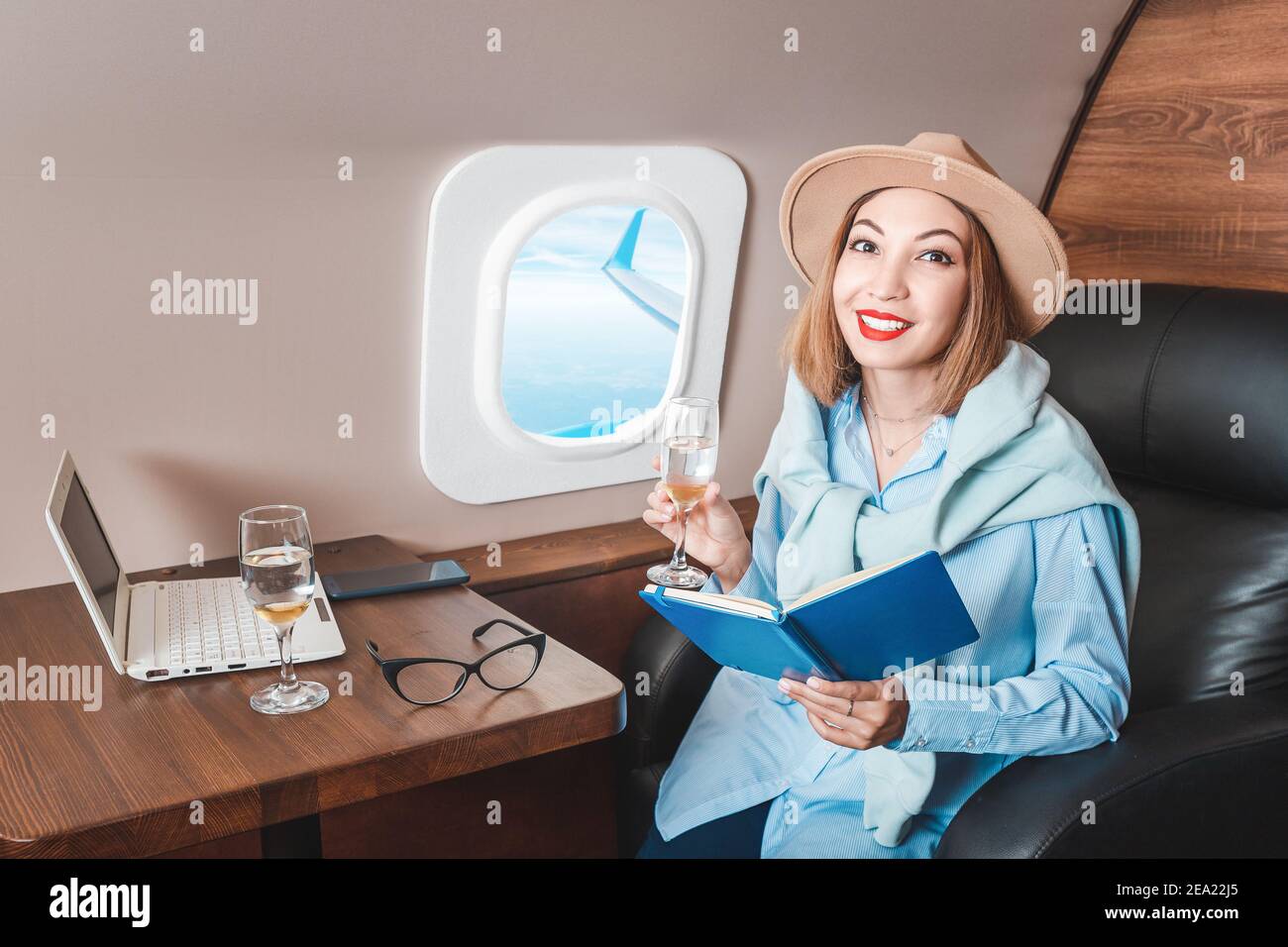 An Asian girl is flying on a plane in business class and drinking a