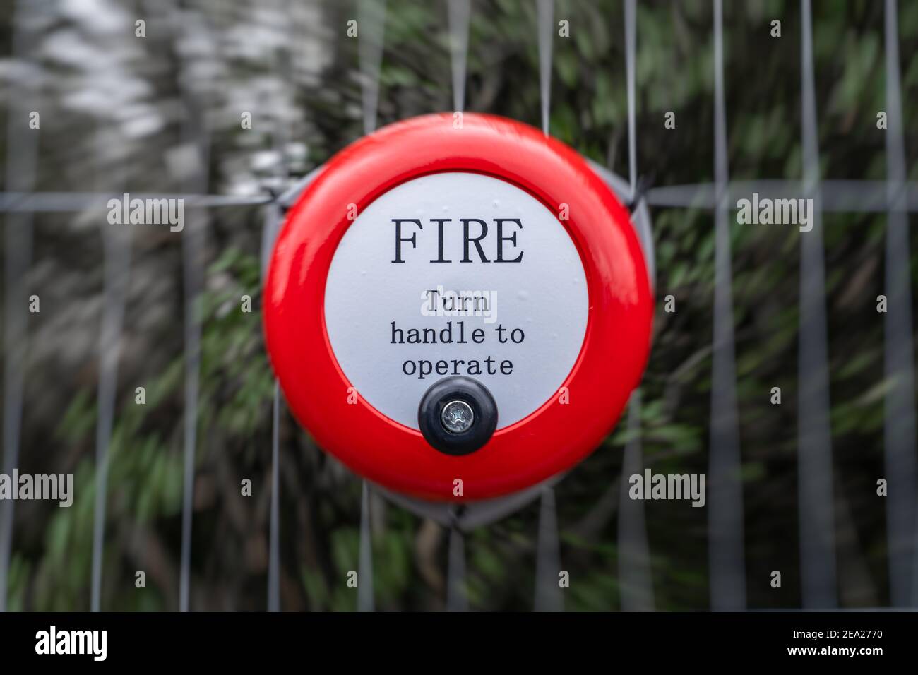 Bright red metal fire alarm bell turn handle to operate alert manual steel  ringing on construction building site attached to metal fence Stock Photo -  Alamy