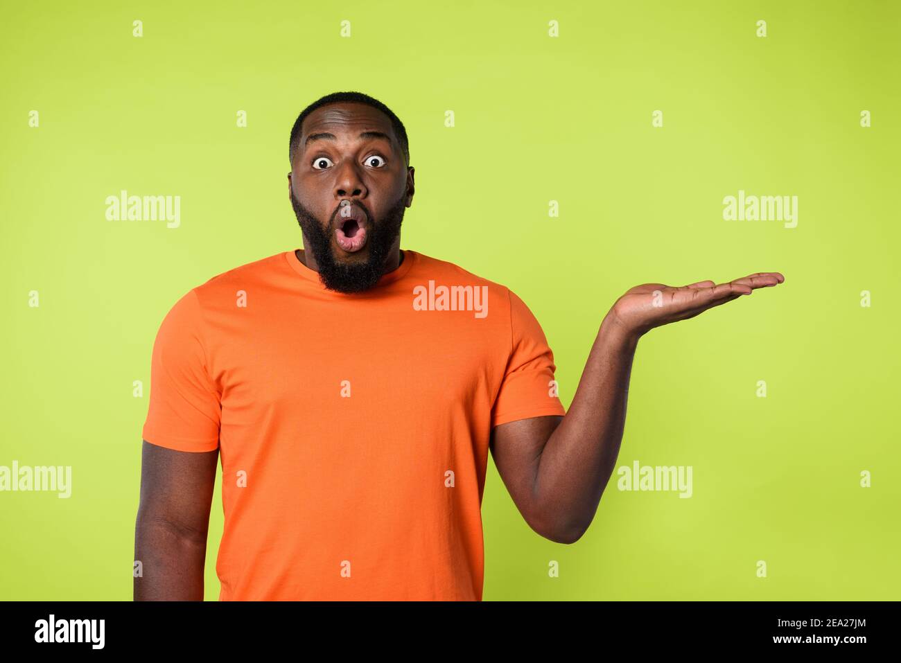 Surprised black man holds something in hand. Yellow background Stock Photo