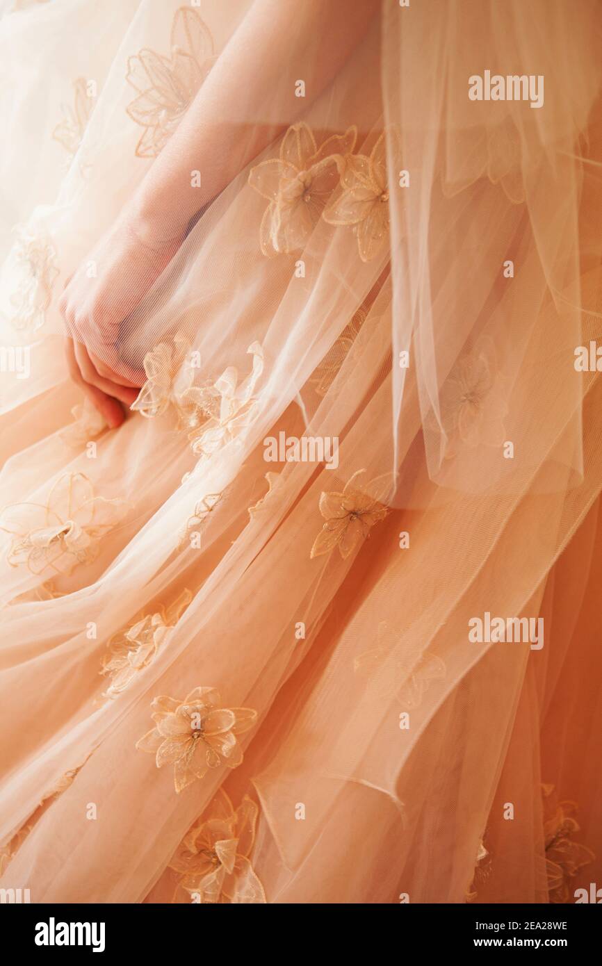 Detail of a wedding dress with a peach color tulle skirt. Stock Photo