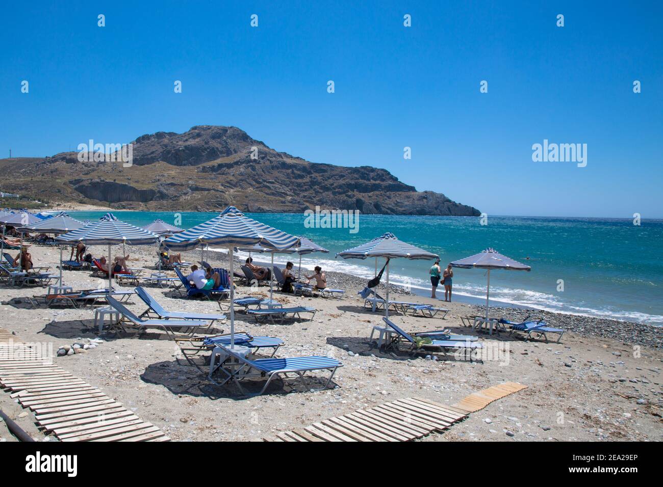 Plakias beach is in Crete, Greece:  Plakias beach on the south coast of the Greek island of Crete. Blue  umbrellas and bedstones on the beach. Stock Photo