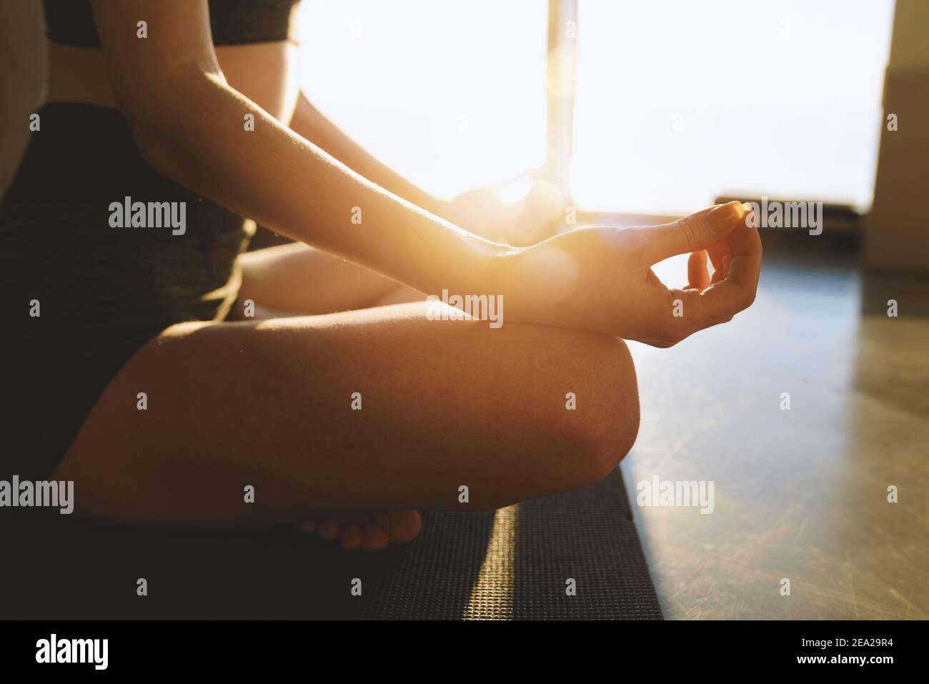 Young girl relaxing in yoga position in front of a bright window Stock Photo