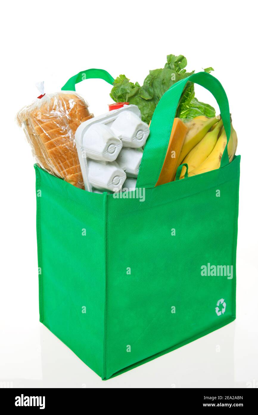 A reusable grocery bag with recycle symbol, filled with basic groceries. Stock Photo