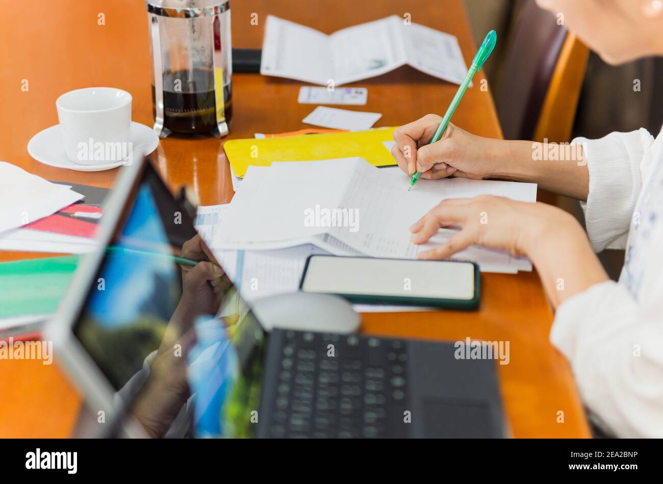 Woman paying bills online and writing notes at home. Stock Photo