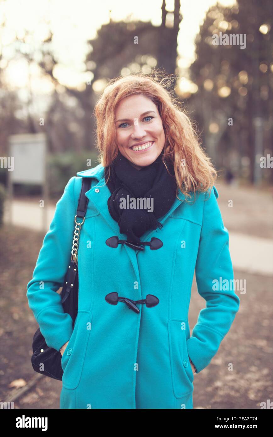 Happy young redhead Caucasian woman smiling in park at winter Stock Photo