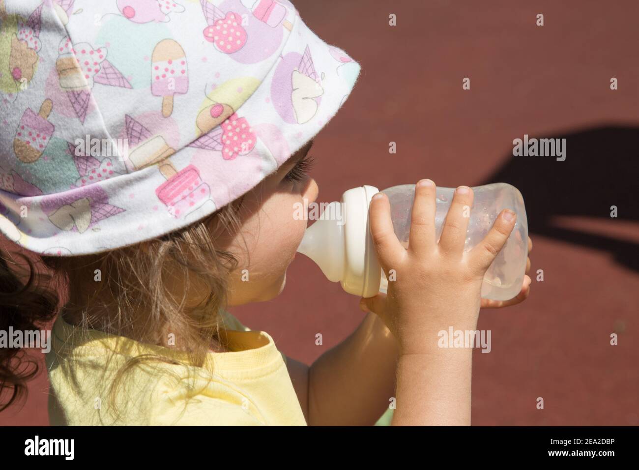 Protecting Young Children From Extreme Heat concept. Baby in panama drinks a bottle of water. Stock Photo