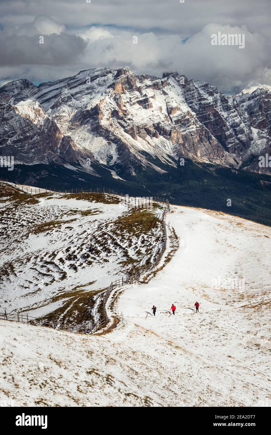 Hikers in the sunshine in front of a snow-covered Dolomites landscape with the Heiligkreuzkofel in the Fanes-Sennes-Braies mountains in autumn Stock Photo