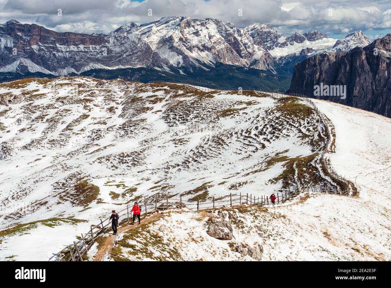 Hikers in the sunshine in front of a snow-covered Dolomites landscape with the Heiligkreuzkofel in the Fanes-Sennes-Braies mountains in autumn Stock Photo