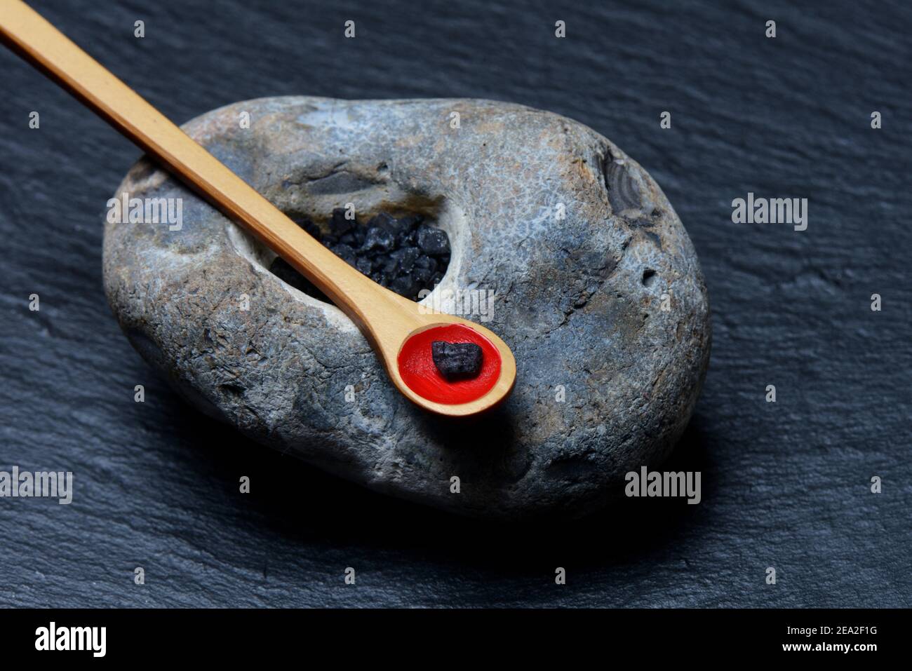 Hawaiian salt, black Hawaiian salt in stone with depression and spoon, with activated carbon, gourmet salt Stock Photo