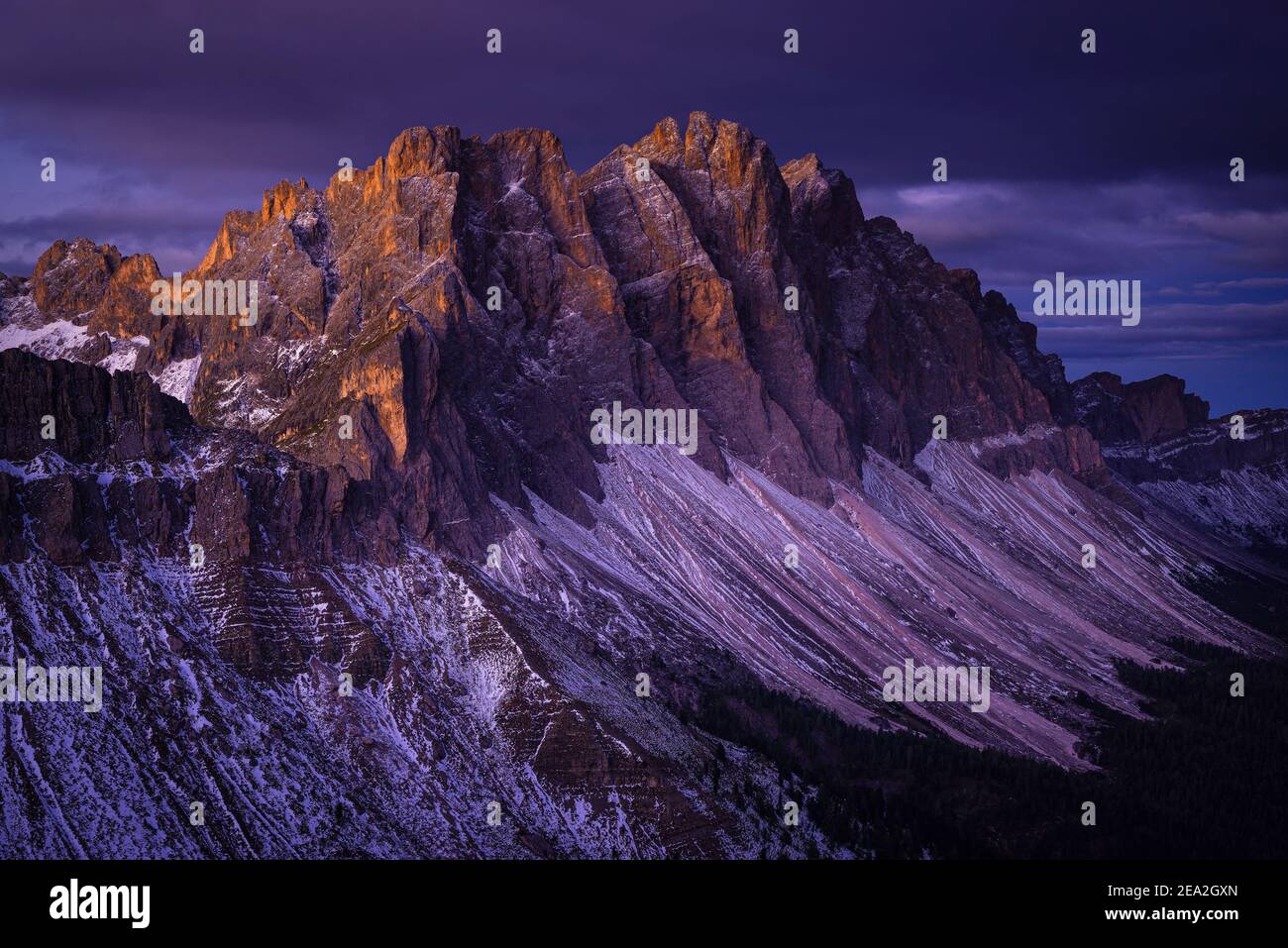 The snowy rock faces and cliffs of the Geisler peaks of the Puez-Odle mountains glow at dawn, Dolomites, South Tyrol, Italy Stock Photo