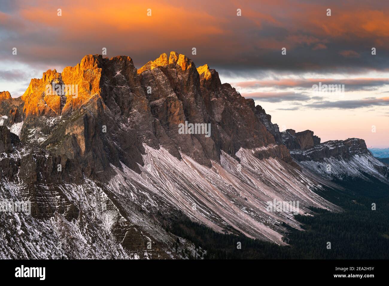 Clouds, cliffs and the peaks of the Puez-Odle mountains glow golden in the sunlight at sunrise at the Dolomites, Villnöß valley, Sout Tyrol, Italy Stock Photo