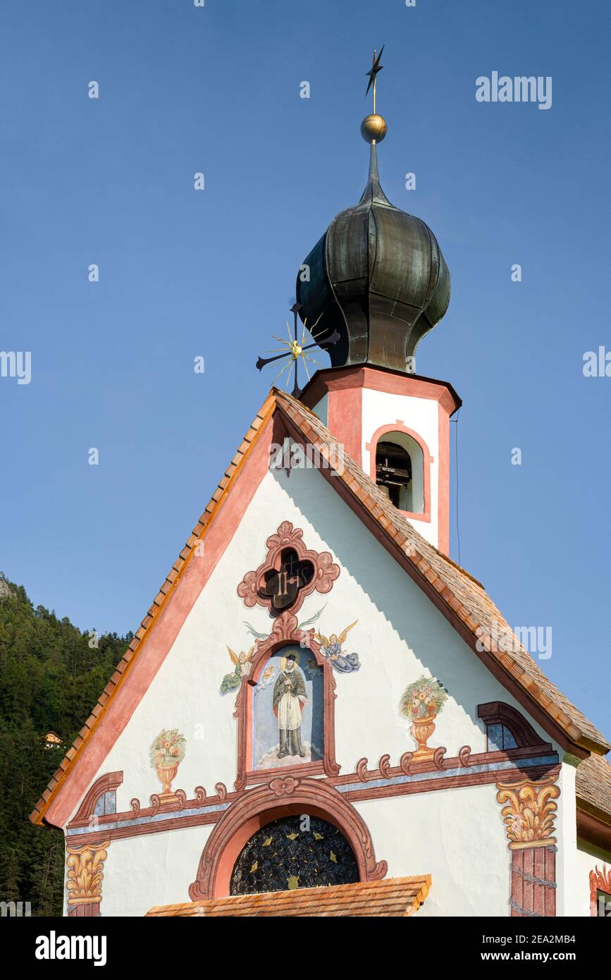Front and steeple of Baroque Ranui Chapel in Villnöß in front of Puez-Odle mountains in the Dolomites in sunshine, Puez-Geisler, South Tyrol, Italy Stock Photo
