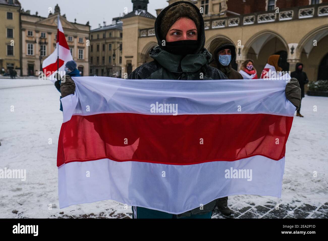 A protester holds a historical white-red-white flag of Belarus during a protest in solidarity with Belarus political prisoners at Krakow's Unesco Listed Main Square. Stock Photo