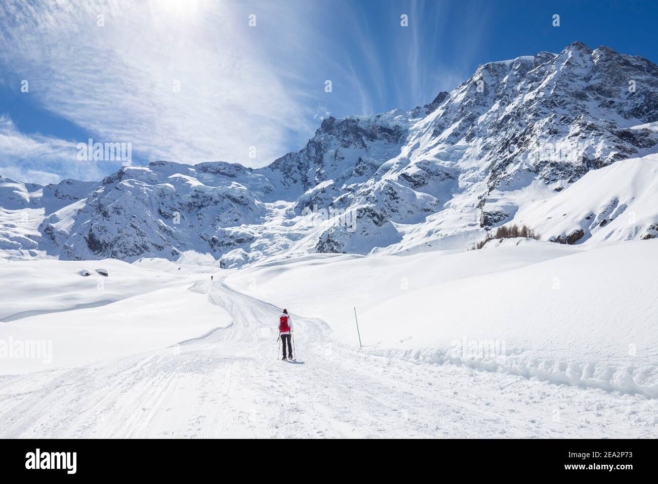 A trekker with snowshoes walking on the winter track on  Belvedere Glacier at the foot of the East face of Monte Rosa Massif. Macugnaga, Anzasca Valle Stock Photo