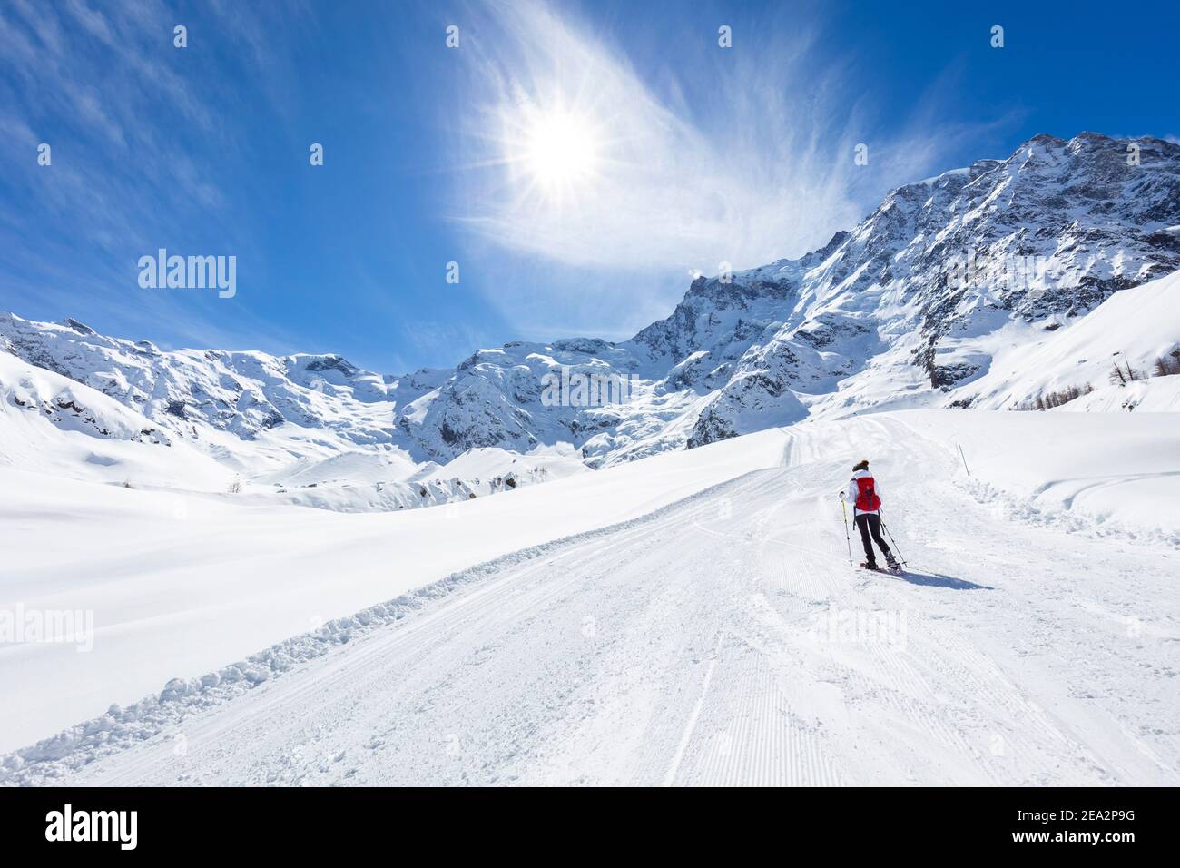 A trekker with snowshoes walking on the winter track on  Belvedere Glacier at the foot of the East face of Monte Rosa Massif. Macugnaga, Anzasca Valle Stock Photo
