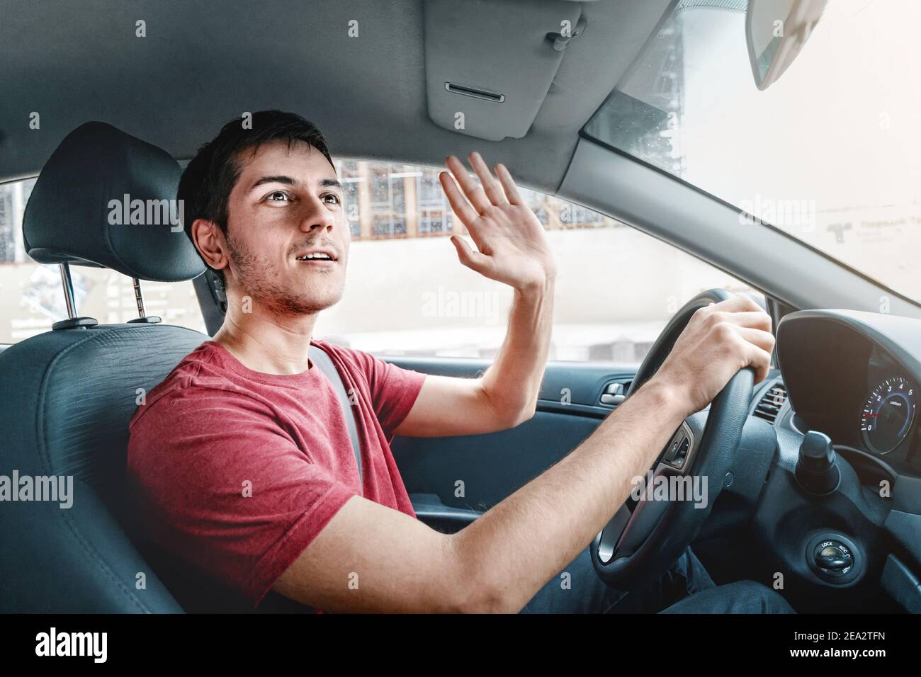 Joyful and careless car driver raises his hand in thanks for giving way. Traffic rules and politeness concept Stock Photo