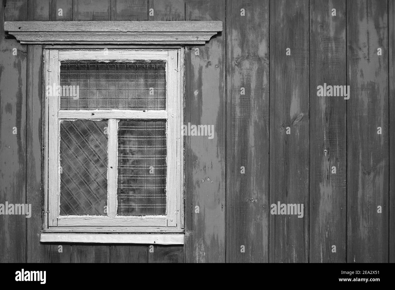 A wooden wall with an old rustic window. The concept of poverty and dilapidation. Stock Photo