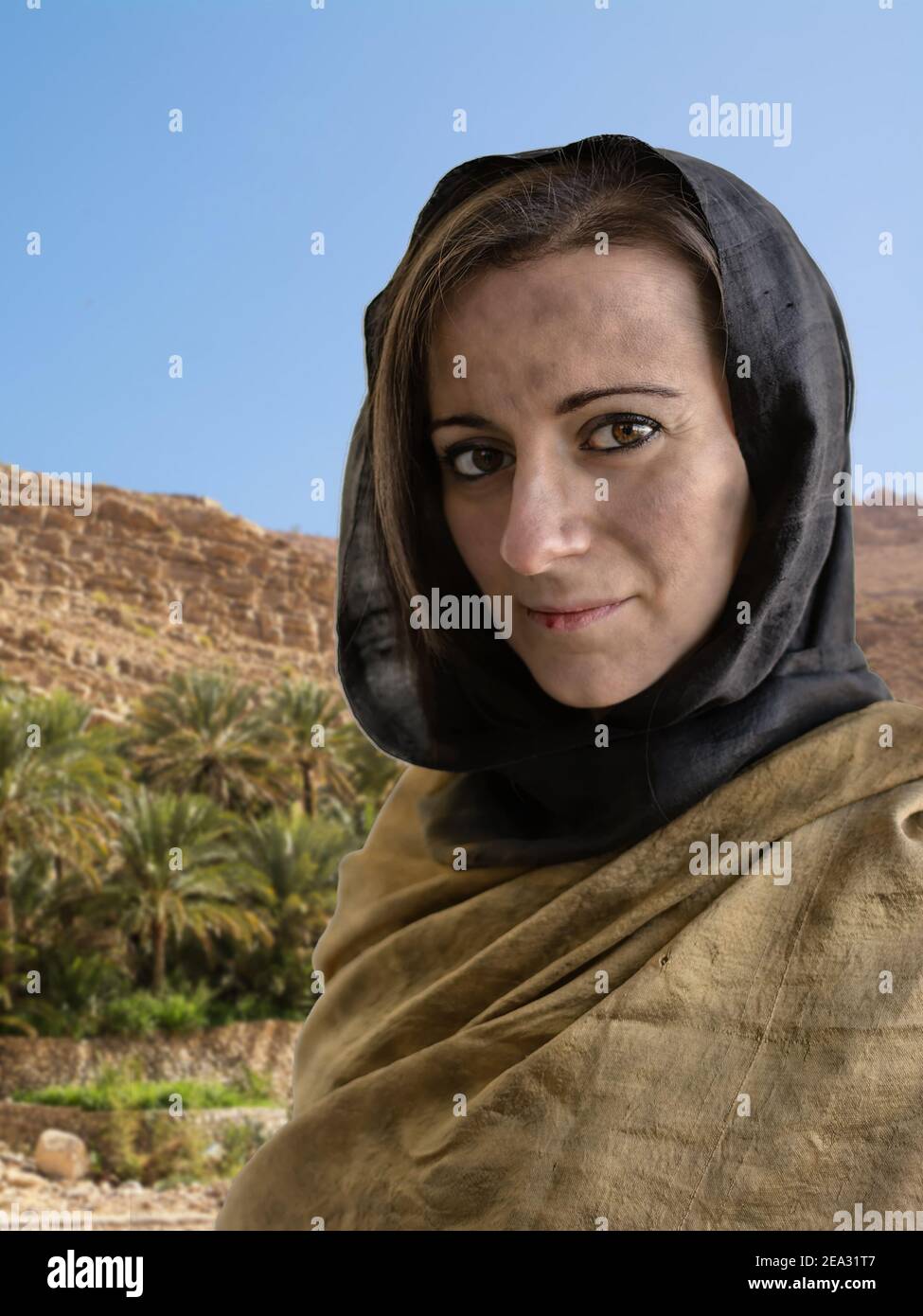 Portrait of woman with hijab and in the background palms and arid environment Stock Photo