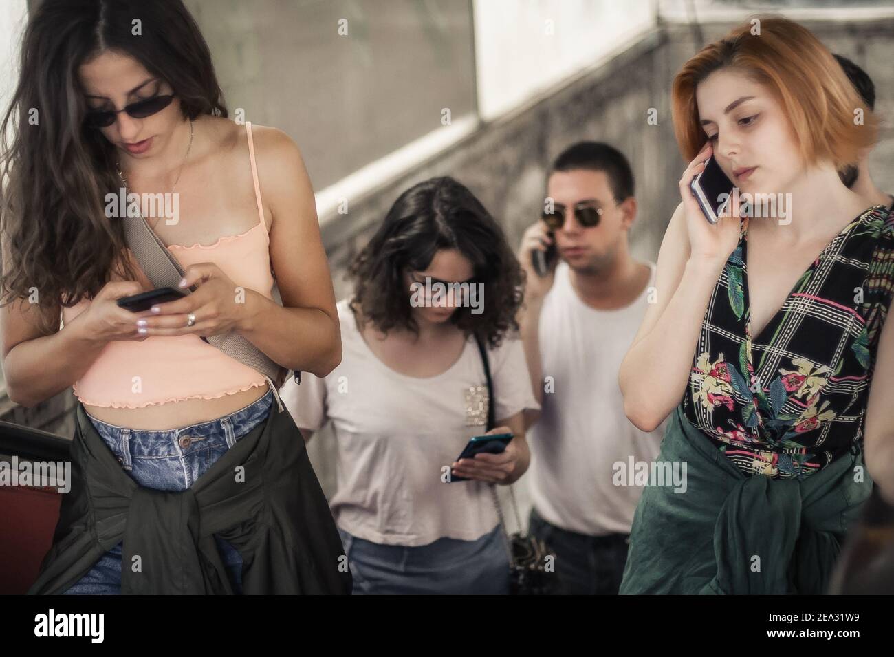 Friends Talking Using Phones Group of friends talk on smartphones while standing on escalator ...