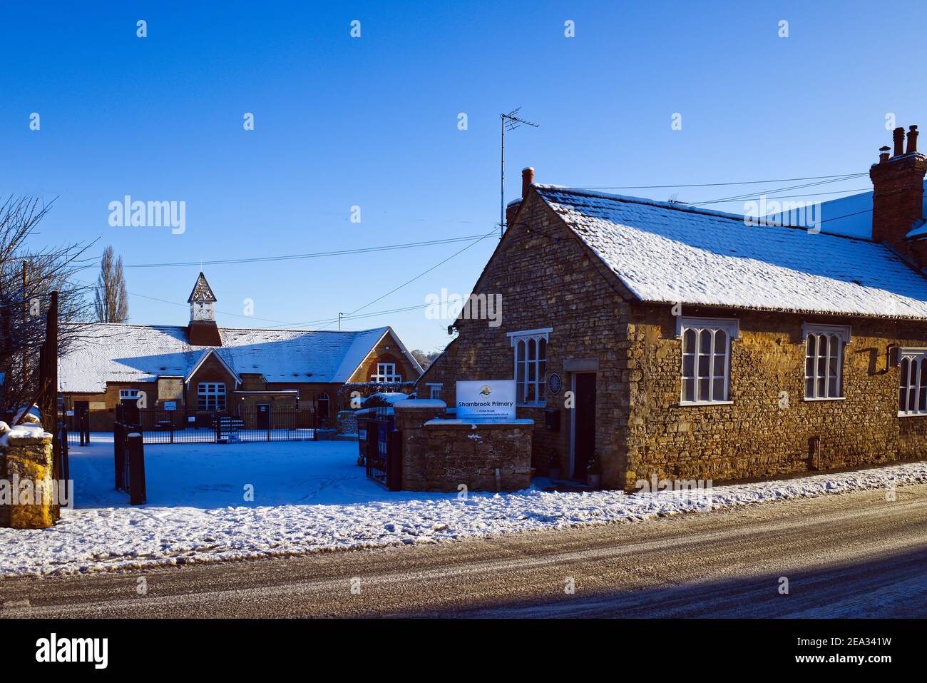 Sharnbrook High Street, Bedfordshire, England, UK - Sharnbrook village primary school winter scene after snow Stock Photo