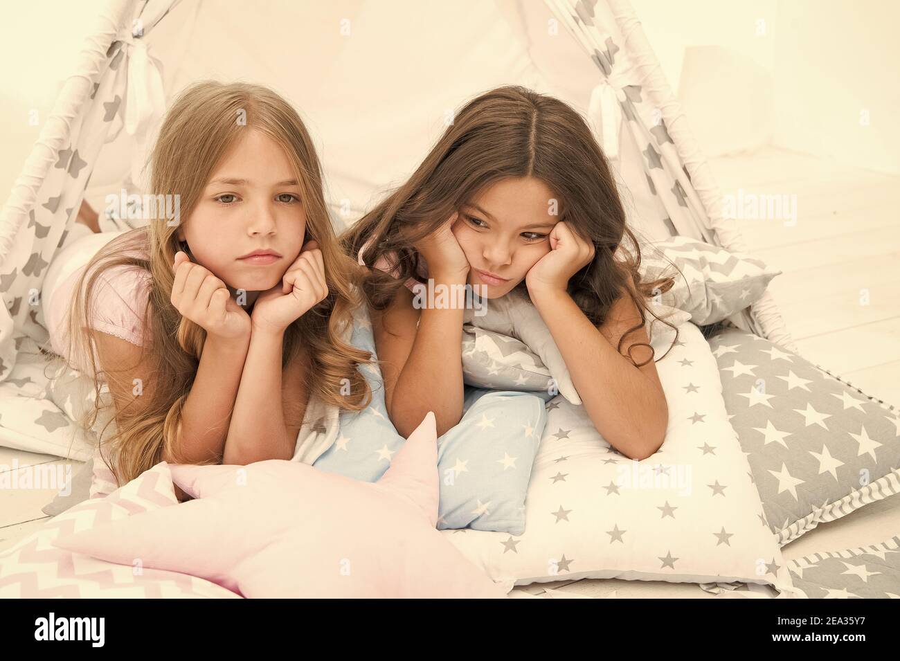 We dont want to go to bed. Unhappy children lie on bed cushions. Home accessories. Bed time routine. Bedtime. Night nursery. Good night. Resting cozy in bed. Stock Photo