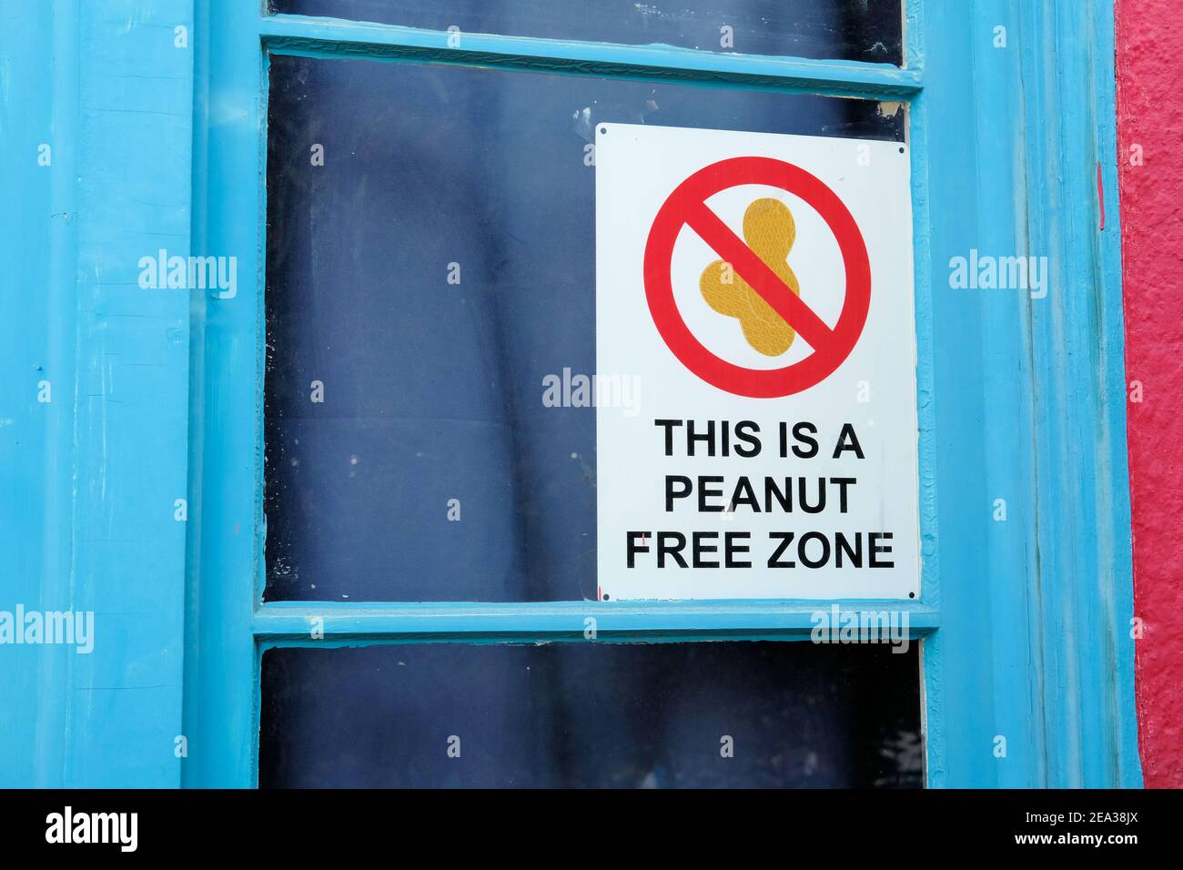Sign altering patrons that this is a peanut free zone, on a window outside a home or business; no peanuts allowed; allergy alert and warning placard. Stock Photo