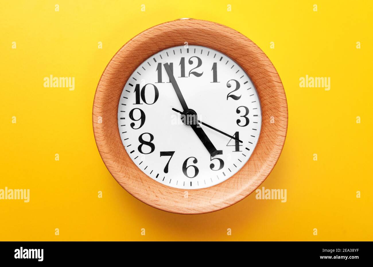 Wooden round clock on yellow background Stock Photo Alamy