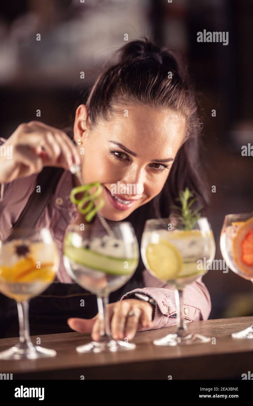 Bartender loving her job decorates gin tonic cocktails in glasses on a