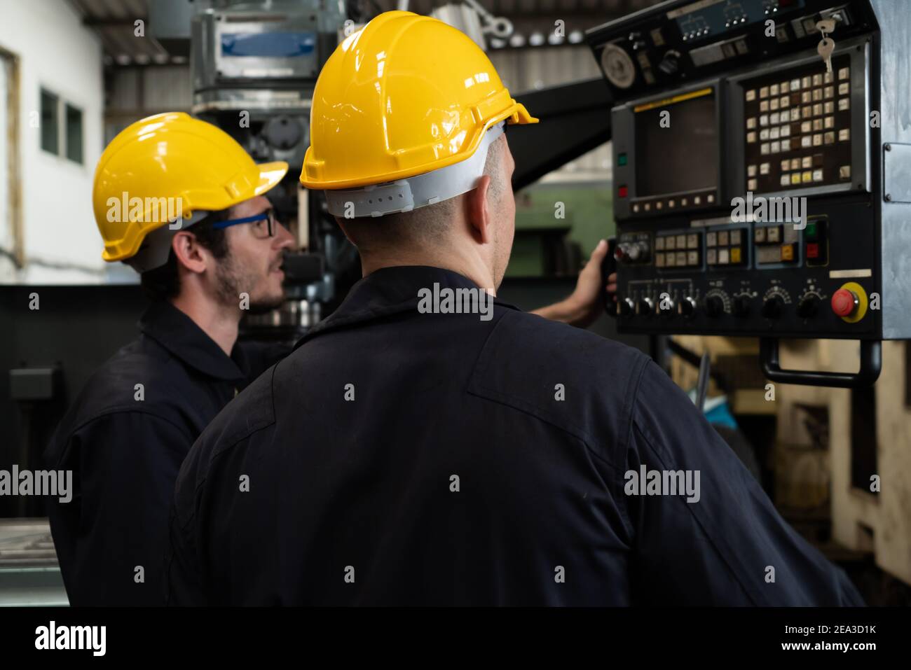Group of skillful factory workers using machine equipment in