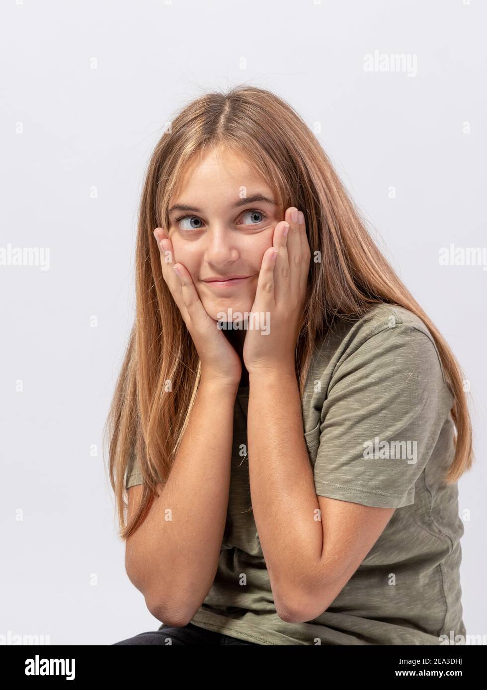 Young smiling girl looks to the side with sly and surprised expression Stock Photo