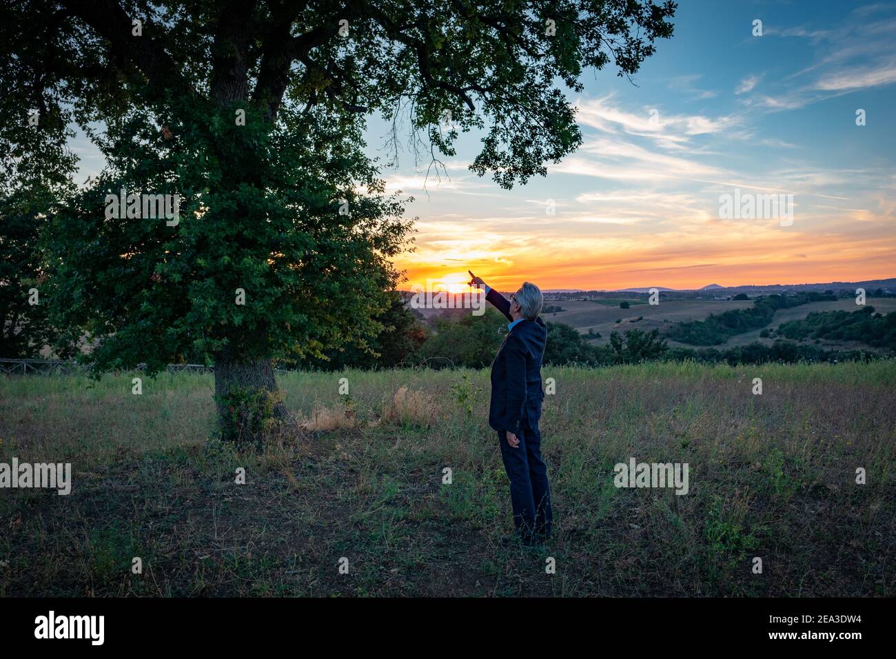 Senior botanist talking with the magic tree at sunset Stock Photo