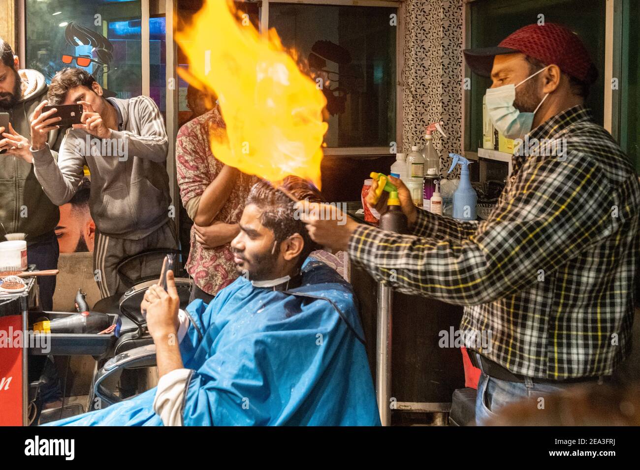 In Lahore, a hairdresser has developed a unique technique to cut gentlemen's hair: he sets the hair ablaze Stock Photo