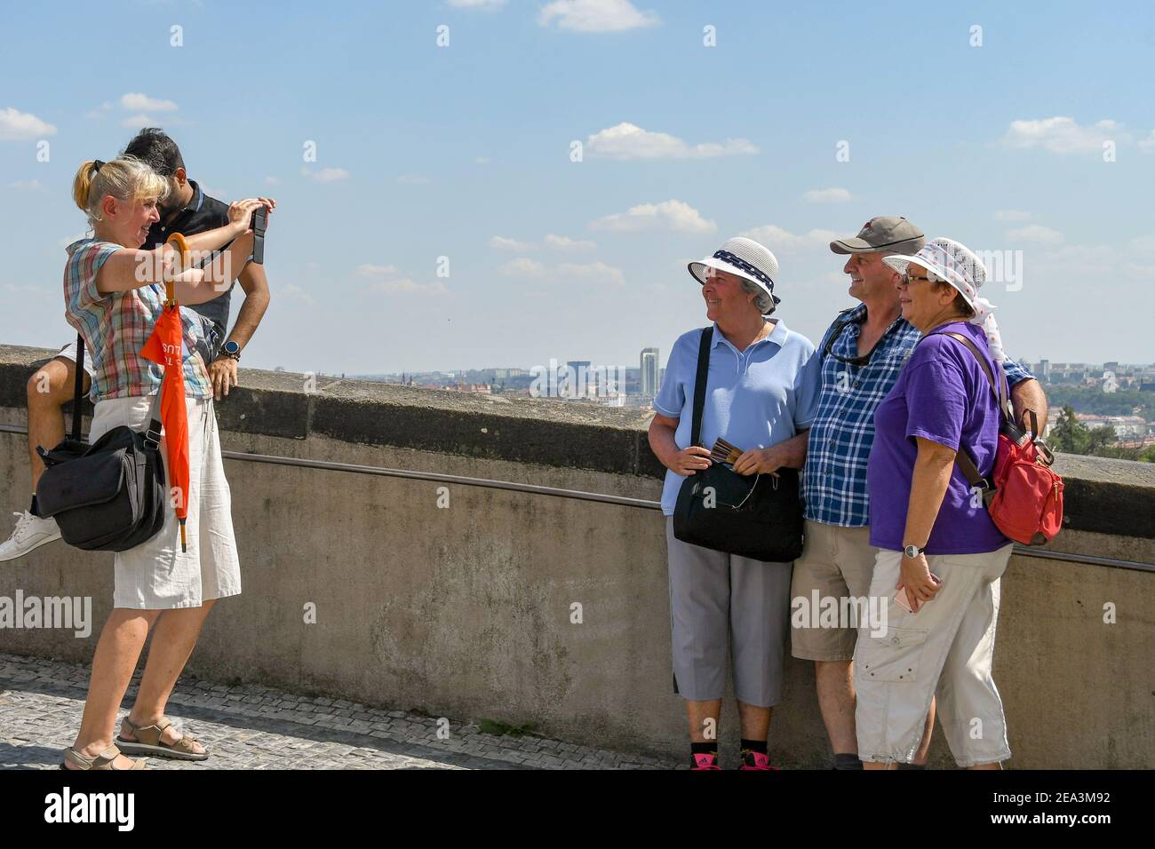 PRAGUE, CZECH REPUBLIC - JULY 2018: Person taking a picture of people posing together at a viewing point near Prague Castle Stock Photo